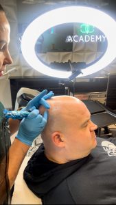 Scalp Micropigmentation training course. Showing procedure on a bald male.