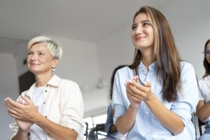 Two students smiling and clapping after completing their lip blush training course.