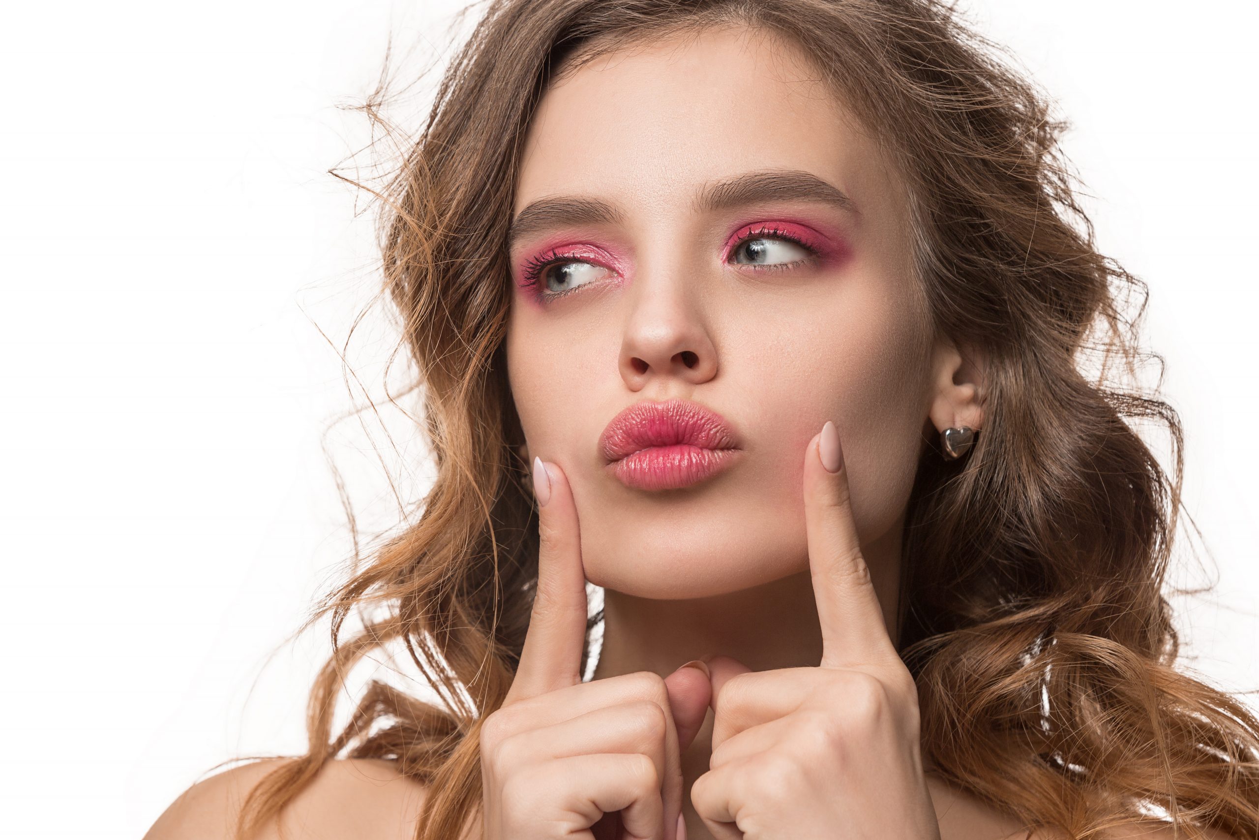 A young woman with her index fingers placed either side of her lips on her face to show her lip blush.