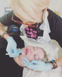 A lip blush artist pre-drawing lips before procedure.