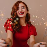 Woman with red hair holding sparklers and laughing to celebrate the new year and her SPMU New Year's resolutions. 