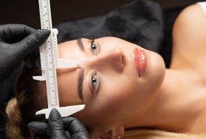 A beautiful woman having her eyebrows measured after a cosmetic procedure.