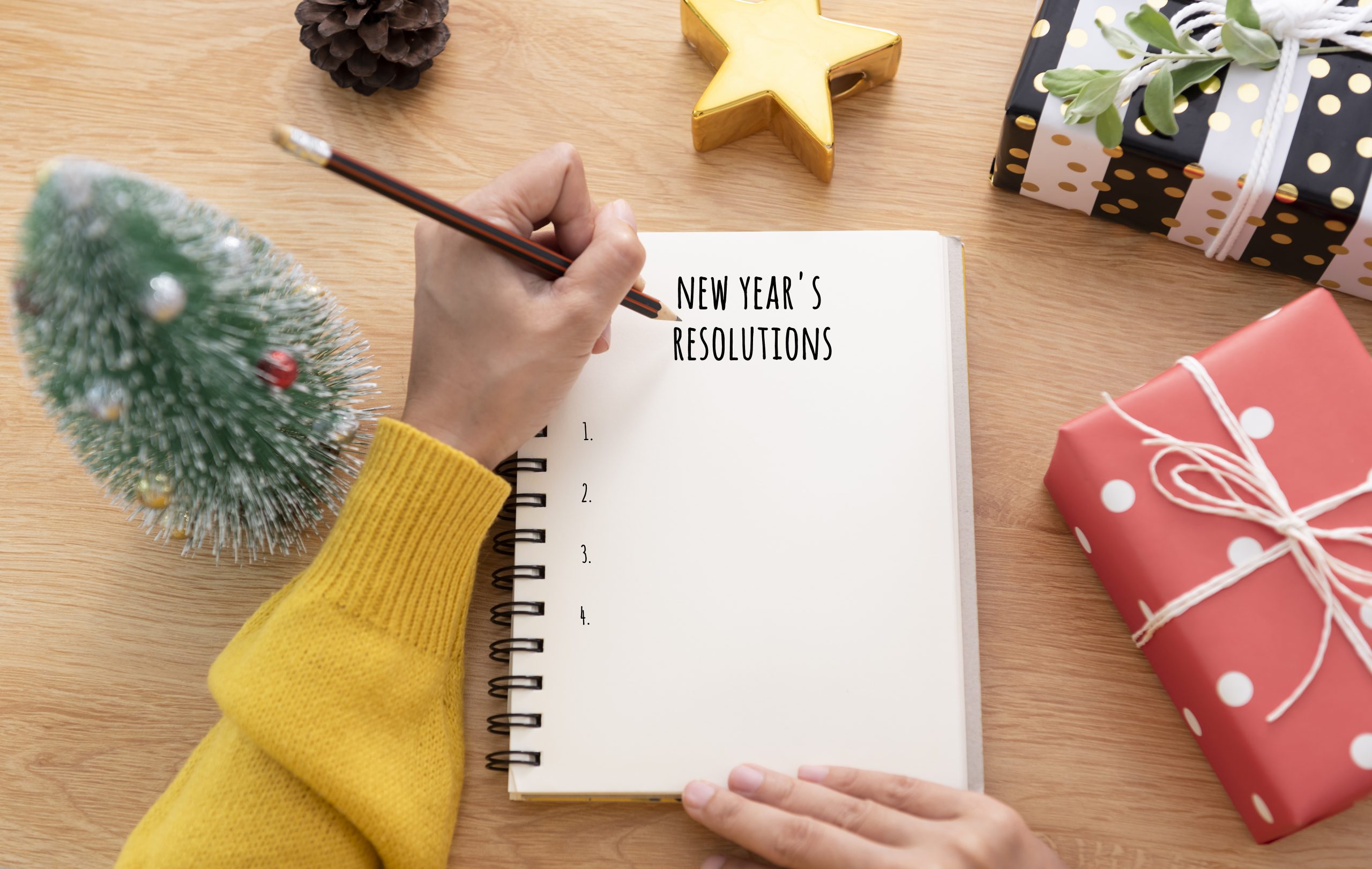 Woman handwriting about to write her SPMU New Year's resolutions her notebook.